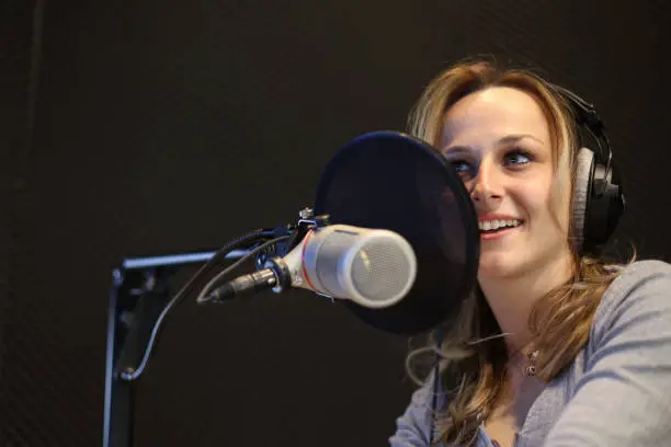Young woman working as a presenter at a radio station. About 25 years old, Caucasian female.