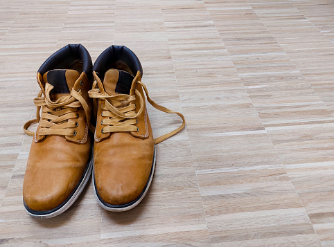 Pair of old light brown leather boots on wooden floor.