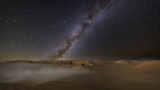 Misty night with milky way over idyllic desert landscape and oasis with palm and dunes