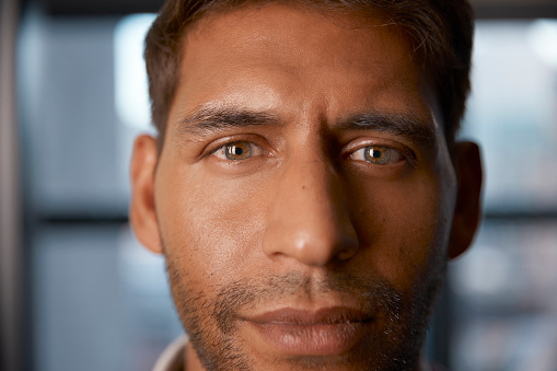Portrait, vision and closeup with a handsome man looking serious or thoughtful against a blurred background. Face, focus and mindset with the eyes of a male person feeling confident or optimistic