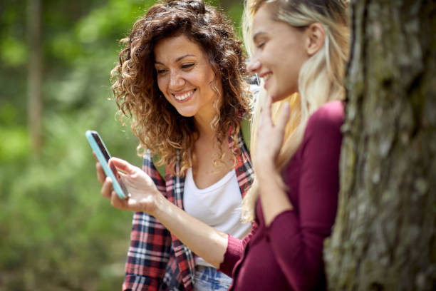 istock girls at forest watching mobile phone 1487474198