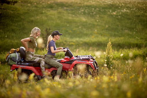 Two handsome woman driving quad together in the nature; Active vacation concept