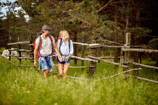 A young couple in love enjoys chatting while hiking on a beautiful day in the nature. Hiking, relationship, nature, activity