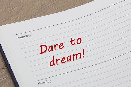 A Dare to dream diary reminder message open on desk
