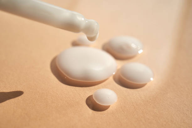 istock Drops of white cosmetics on a beige background with a dropper. 1487475865