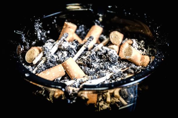 istock Overhead of burning cigarette in ashtray on black background. 1487477209
