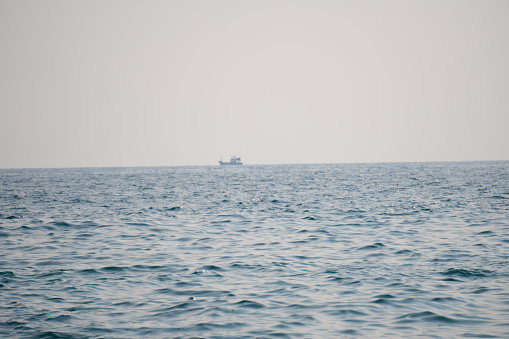 Minimalistic shot of boat in the big ocean. Boat in the sea background . View of the Arabian sea with a boat in the distance as seen from Kakolem Beach at Goa in India. Distant boat with sea waves.