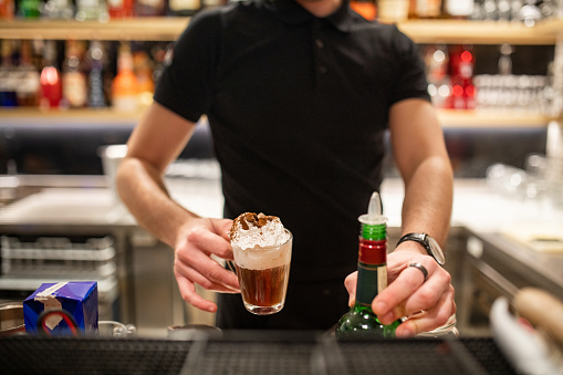 Unrecognizable Caucasian barista serving a coffee on a bar counter