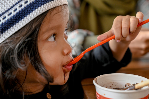 Asian toddler eating chocolate ice cream