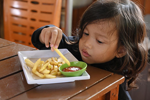 Asian toddler eating French fries