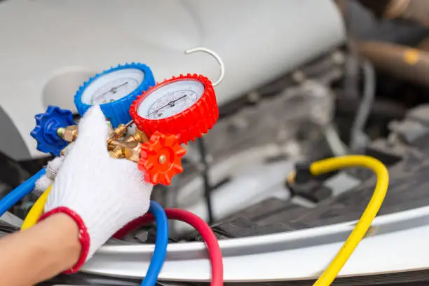 Photo of Repairman holding monitor tool to check and fixed car air conditioner system, Technician man check car air conditioning system refrigerant recharge, Air Conditioning Repair