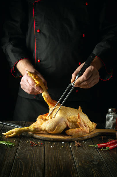 istock Cooking Southern fried chicken in the restaurant kitchen by the chef. Raw chicken on a cutting board. Fork in the cook hand. 1487480896