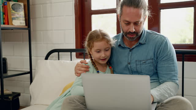 Father and daughter using laptop on bed in bedroom, education concept, family relationship