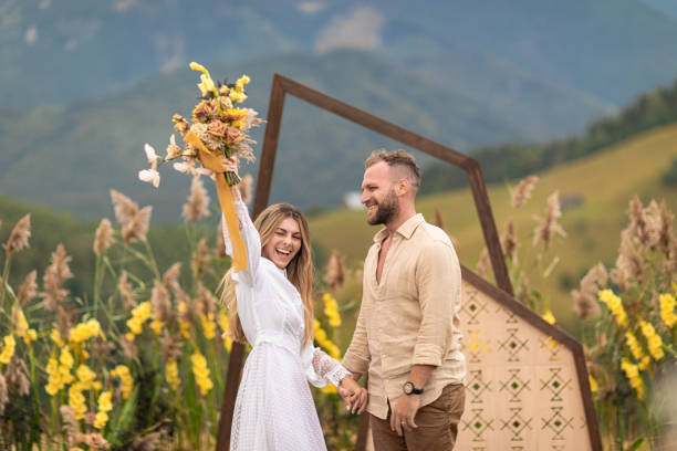 natural beauty and simplicity of a couple who eloped in the mountains surrounded by natural decor and flowers. The bride is wearing a beautiful white dress and both are beaming with joy and love. natural beauty and simplicity of a couple who eloped in the mountains surrounded by natural decor and flowers. The bride is wearing a beautiful white dress and both are beaming with joy and love. eloping stock pictures, royalty-free photos & images
