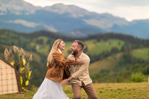 couple runs, laughs, bride jumps on groom's back, showing deep love, with mountains in background.