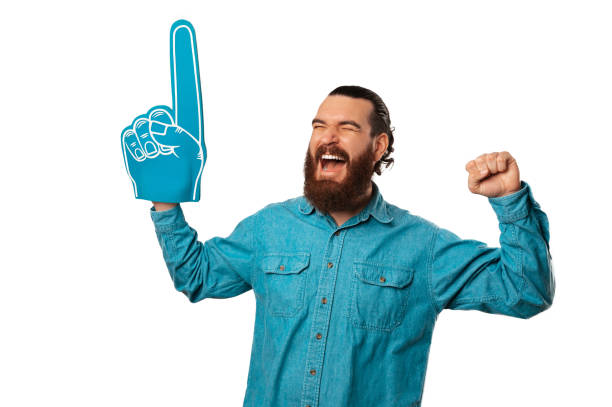 istock Ecstatic bearded man is wearing fan foam finger glove making winner gesture. 1487482566