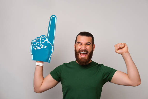 Excited man wearing foam finger fan glove while making the winner gesture. stock photo