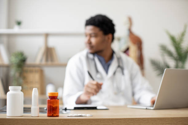 istock Medication bottles on desk against working doctor background 1487486188