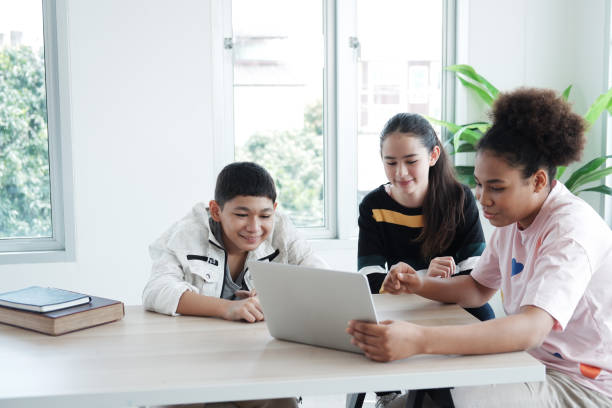 istock Smiling Caucasian and African student is online learning and make homework for home school. They are researching knowledge with internet on laptop in classroom. Education and Technology Concept. 1487494370