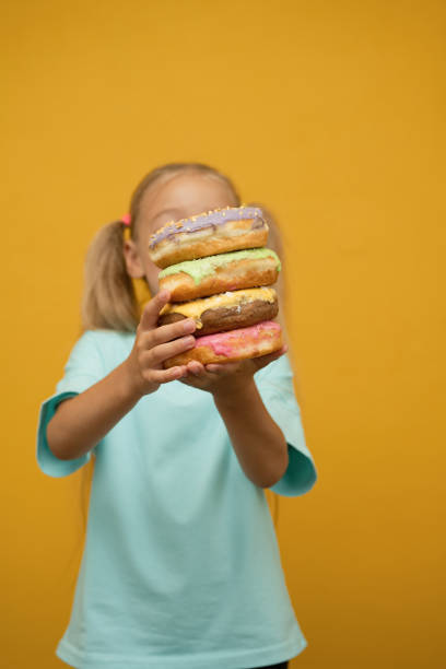 istock Funny girl with donuts on a yellow background 1487494566