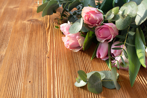 Bouquet of pink roses for mothers day on rustic wood. Background for congratulation with space for text.
