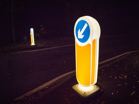 Yellow, white and blue keep left sign in the UK - night photography