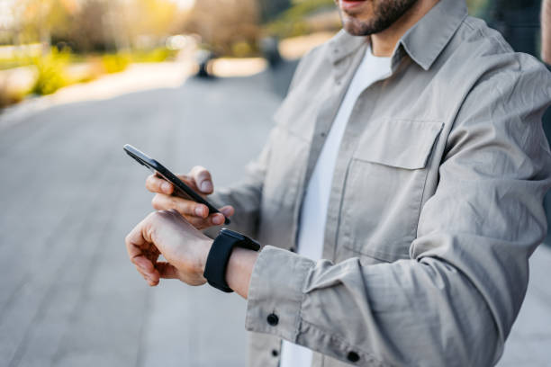 istock Young Man Using Phone And A Smart Watch Outdoors 1487500195