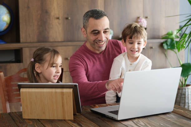 istock Children And Father Using Smart Phone, Laptop Computer And Digital Tablet At home, Cross Device Group Concept 1487500930