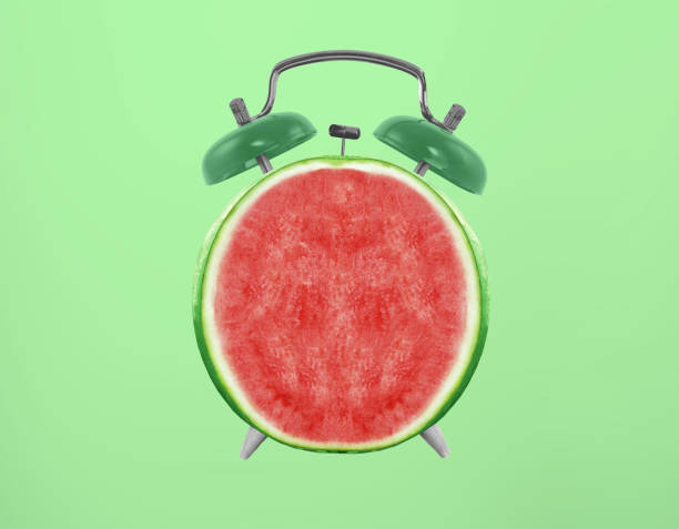 istock Delicious red watermelon with alarm clock on a green background, creative idea 1487502072