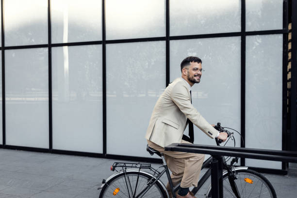 istock Businessman riding bicycle in front of modern office building. 1487502249