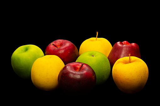 Red,green and yellow fresh juicy apple fruits on black background .Image made in studio.