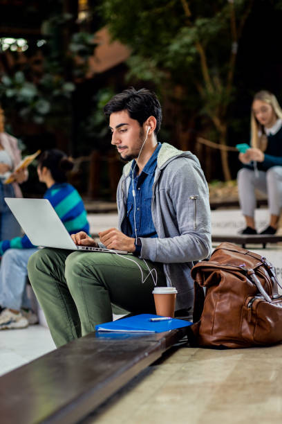 istock Portrait of male student siting in campus using laptop. 1487502843