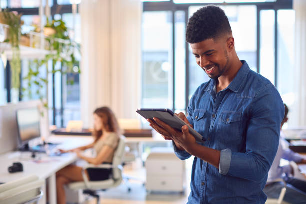 istock Young Smiling Businessman With Digital Tablet Standing And Working In Modern Office 1487503270