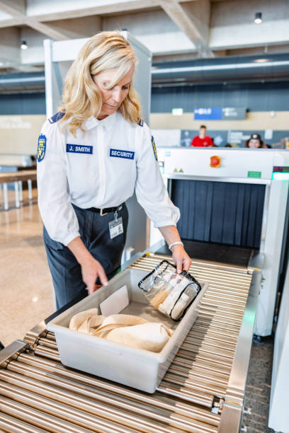 백인 여성 공항 보안 요원이 엑스레이 기계 내부의 트레이를 밀고 있다 - security security staff customs security system 뉴스 사진 이미지
