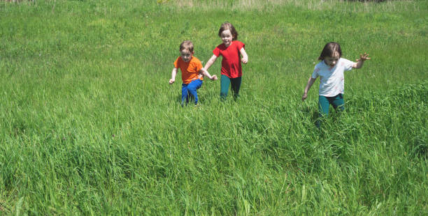 Children hiking in Alps mountains. Kids run at snow covered mountain in Austria. Spring family vacation. Little boy and girl on hike trail in blooming alpine meadow. Outdoor fun and healthy activity.