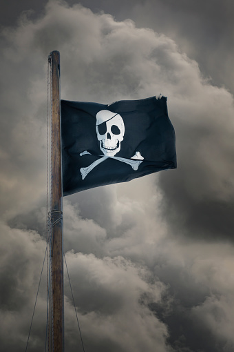 Jolly Roger. Pirate flag in the top of an old sailing boat mast.
