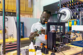Young African man examining a 3d printed part at creative lab