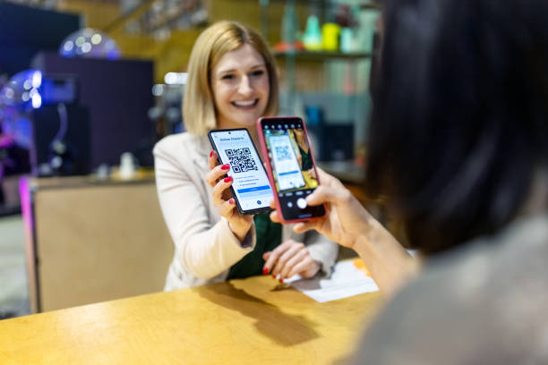 istock Happy woman showing QR code on her phone to the receptionist at makers space office 1487507994