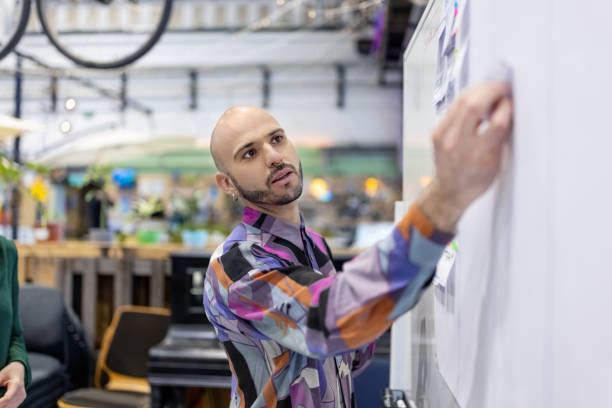 Man sticking an adhesive note on a whiteboard in the creative office
