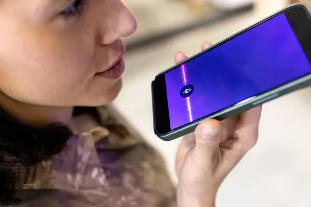 Photo of Close-up of a woman recording voice message on her mobile phone