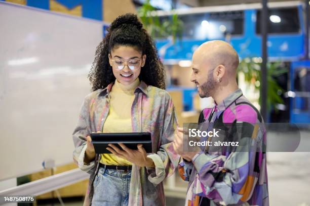 Two Creative People Walking Together And Discussing A Project On A Digital Tablet At Makers Space Stock Photo - Download Image Now