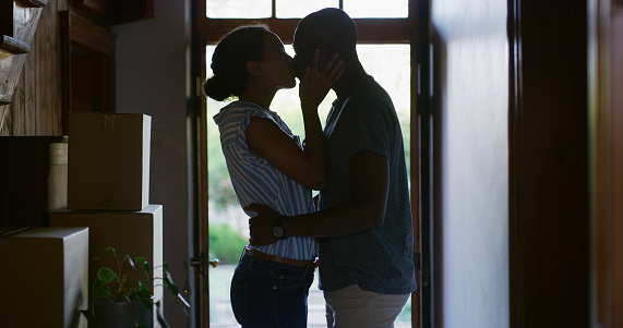 Kiss, ]real estate and silhouette of couple at new house for celebration, affectionate and hugging. Happiness, moving and mortgage with man and woman at front door for homeowner, relocation and love