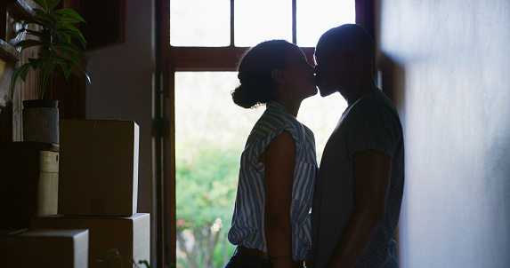 Kiss, couple and home with shadow at a front door with love, support and marriage. Happiness, romance and kissing of a African woman and man together care in a house with romantic silhouette
