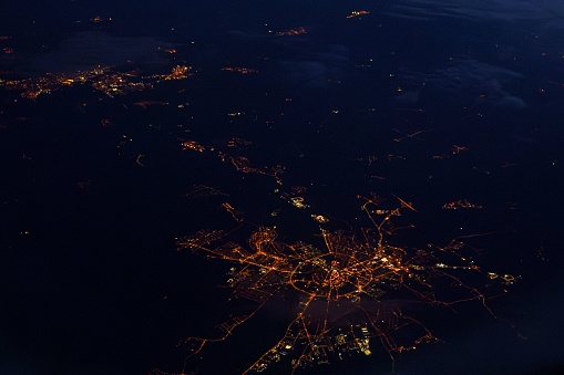 An aerial view of illuminated city at night, taken from a commercial airliner window