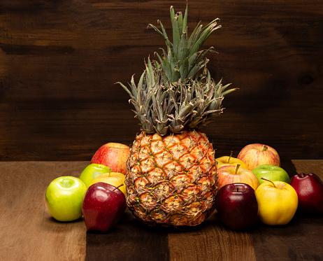 Still life of healthy organic fruits on pineapple fruit with apples on wooden background ,Imge made in studio.