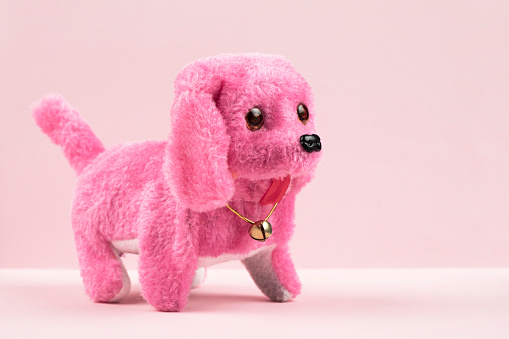 Toy puppy on pink background