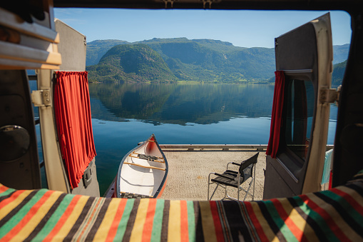 Scenic view of chair and canoe standing near the camper van by the lake