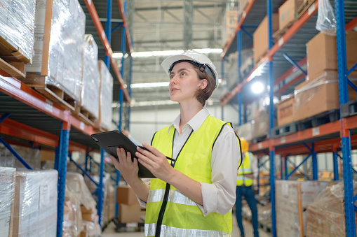 A female manager is checking inventory inside a warehouse.