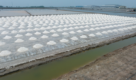 Aerial view of sea salt farm. Pile of brine salt. Raw material of salt industrial. Sodium Chloride mineral. Evaporation and crystallization of sea water. White salt harvesting. Agriculture industry.