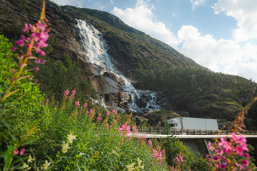 Scenic view of  truck on the road near  the waterfall that falls into fjord in Norway